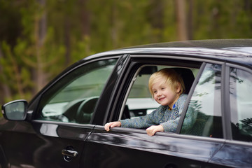 Cute little boy ready for a roadtrip or travel. Family car travel with kids.