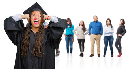 Young graduated black woman wearing braids crazy and desperate, screaming out of control, funny lunatic expressing freedom and wild