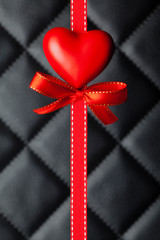 Red heart, bow and ribbon on black quilted leather