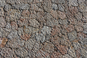 A beautiful texture of an old wall from gray and orange stones with cracks