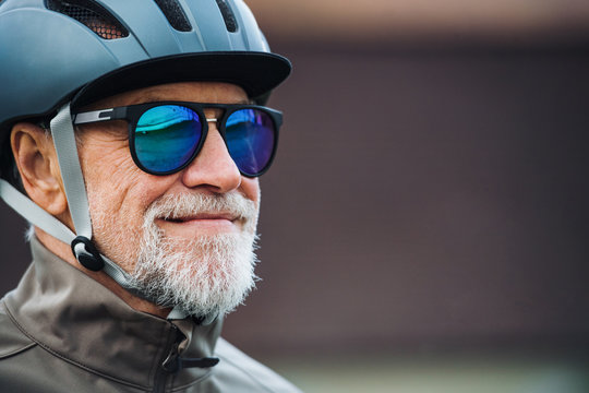 Close-up of active senior man with sunglasses and helmet standing outdoors. Copy space.