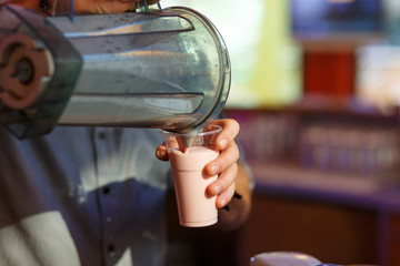 Fototapeta na wymiar The hand of the bartender, pours the milkshake