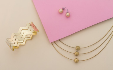 Golden jewelry set on pink and beige background