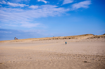 Fototapeta na wymiar Lone woman hiker on the beach, walks alone in the sand on Cape Cod National Seashore in Provincetown