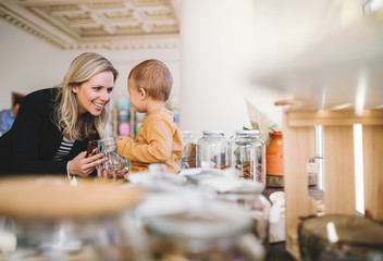 A young woman with a toddler boy buying groceries in zero waste shop.