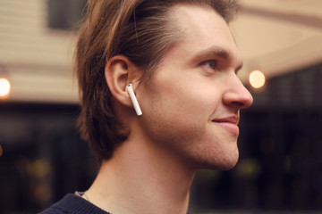 Man in wireless headphones outdoor, street, restaurant. Man listening to e-book, the guy is...