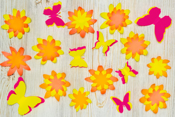 Colorful paper butterflies and flowers on wooden background. Children's developmental activity. Application and origami. Flat lay. Copy space.