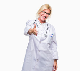 Middle age blonde doctor woman over isolated background smiling friendly offering handshake as greeting and welcoming. Successful business.