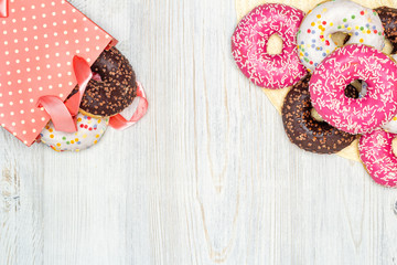 Donuts and gift bag with donuts inside on a wooden table. Flat lay. Copy space. The concept of holiday and gifts