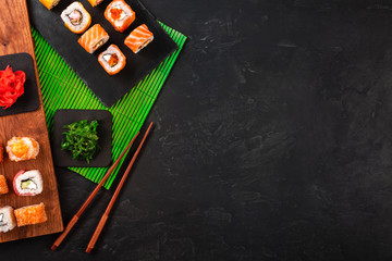 Sushi set with wasabi and ginger on black stone tray on black table. Top view