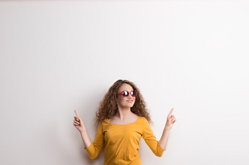 A young beautiful cheerful woman with red sunglasses in studio. Copy space.