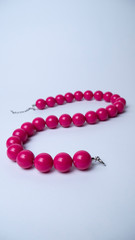 Pink beads on a white background. Accessories. Bijouterie. Vertical photography