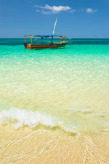 Fototapeta premium white wave in yellow sand and boat at sea in Zanzibar in Tanzania