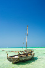 wooden boat in emerald water with clear sky in Zanzibar in Tanzania