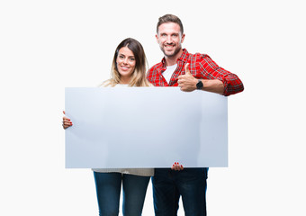 Young couple together holding blank banner over isolated background happy with big smile doing ok...