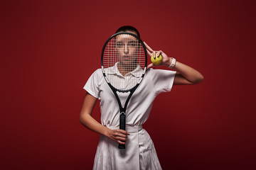 Refuse to Lose! Young tennis player standing isolated over red background with a racket and a ball
