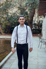 Fototapeta na wymiar Man with white shirt and suspenders walking in park
