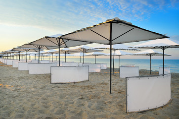 White umbrellas and sun beds on the sea beach. Resorts, vacation and seascapes.