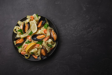 Pasta with seafood on stone table. Mussels and prawns. Top view with copy space.