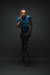 Stronger and faster. Sportsman running over dark background, looking at the camera