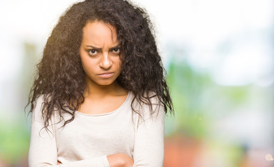 Young beautiful girl with curly hair wearing casual sweater skeptic and nervous, disapproving...
