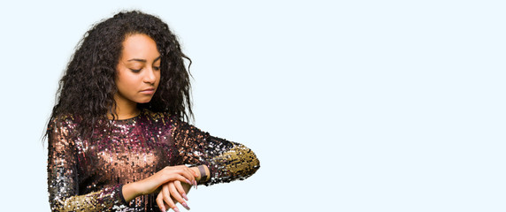 Young beautiful girl with curly hair wearing night party dress Checking the time on wrist watch,...