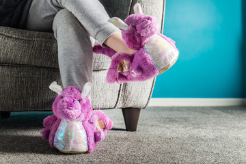 Young girl is wearing cute soft 3d dragon slippers - obrazy, fototapety, plakaty