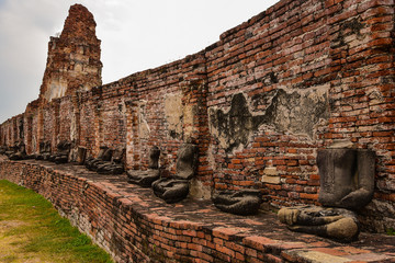 Row of headless buddha statues in temple ruin wall, Ayutthaya Thailand