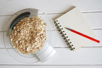 Counting and recording the amount of protein, calories, carbohydrates and fats in food. Flakes from four cereals on kitchen scales. Oatmeal, wheat, barley and rye