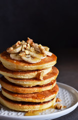 Homemade, hot pancakes with banana, honey and nuts on the kitchen table.