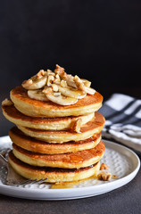 Homemade, hot pancakes with banana, honey and nuts on the kitchen table.