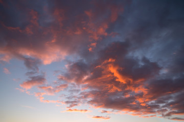 Naklejka na ściany i meble Blue sky with orange and dark clouds, background