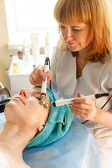 Cosmetologist makes the procedure microcurrent therapy in a beauty salon