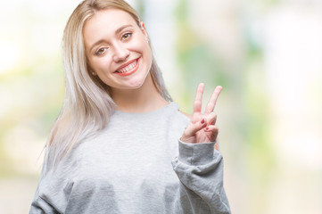 Young blonde woman over isolated background smiling with happy face winking at the camera doing...