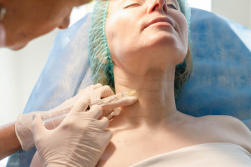 Doctor beautician makes injections in the forehead for patient.