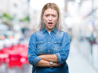 Young blonde woman over isolated background skeptic and nervous, disapproving expression on face with crossed arms. Negative person.