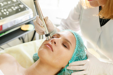 Obraz na płótnie Canvas Cosmetologist makes the procedure microcurrent therapy beauty salon