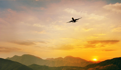 Fototapeta na wymiar Airplane flying over the mountain at sunset