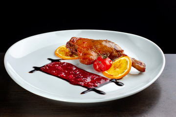 Duck wings with cranberry sauce on a white plate.