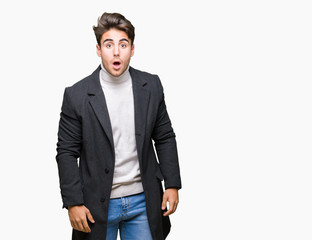 Young elegant man wearing winter coat over isolated background afraid and shocked with surprise expression, fear and excited face.