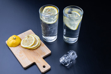 Cold drink in a glass on the kitchen table. Lemon and ice with water the best way to cool off on a...