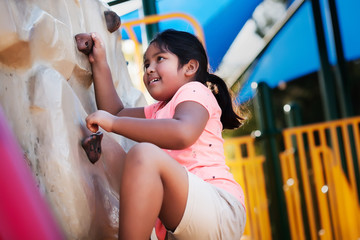 Young and physically active indian girl using her strength to conquer a rock climbing wall.