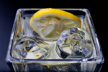 Cold drink in a glass on the kitchen table. Lemon and ice with water the best way to cool off on a...