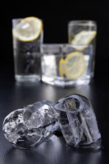 Cold drink in a glass on the kitchen table. Lemon and ice with water the best way to cool off on a summer day.