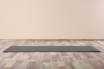 Fototapeta premium Grey yoga mat on floor indoors. Space for text
