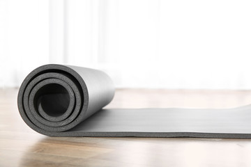 Rolled grey yoga mat on floor indoors