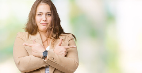 Beautiful plus size young woman wearing winter coat over isolated background Pointing to both sides with fingers, different direction disagree