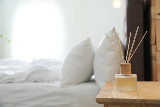 Reed diffuser on nightstand near bed in room. Modern interior
