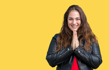 Beautiful plus size young woman wearing a fashion leather jacket over isolated background praying with hands together asking for forgiveness smiling confident.