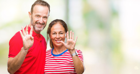 Middle age hispanic couple in love over isolated background showing and pointing up with fingers number nine while smiling confident and happy.